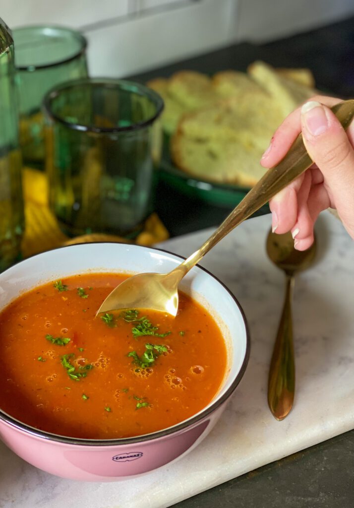 herfstsoep met pompoen, tomaat en paprika in kom met lepel