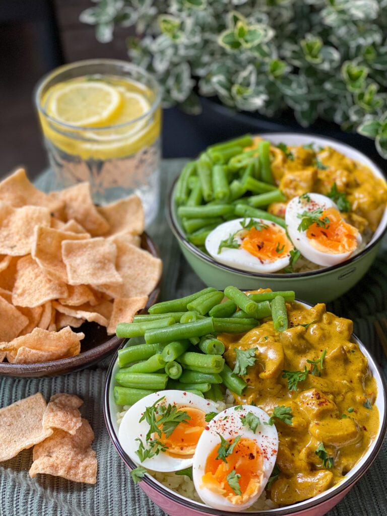 zelfgemaakte kip kerrie in een romige kerriesaus met rijst, boontjes en gekookt ei erbij.