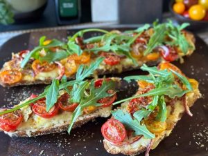 stokbrood met gesmolten kaas en tomaat uit de oven geserveerd met rucola