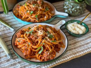 spaghetti in tomatensaus met gehakt, geserveerd met geraspte kaas op rond bord