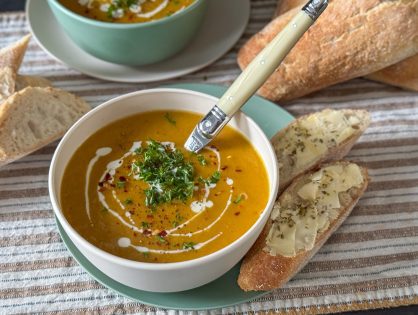 Zoete aardappelsoep met prei in witte kom met peterselie en chilivlokken