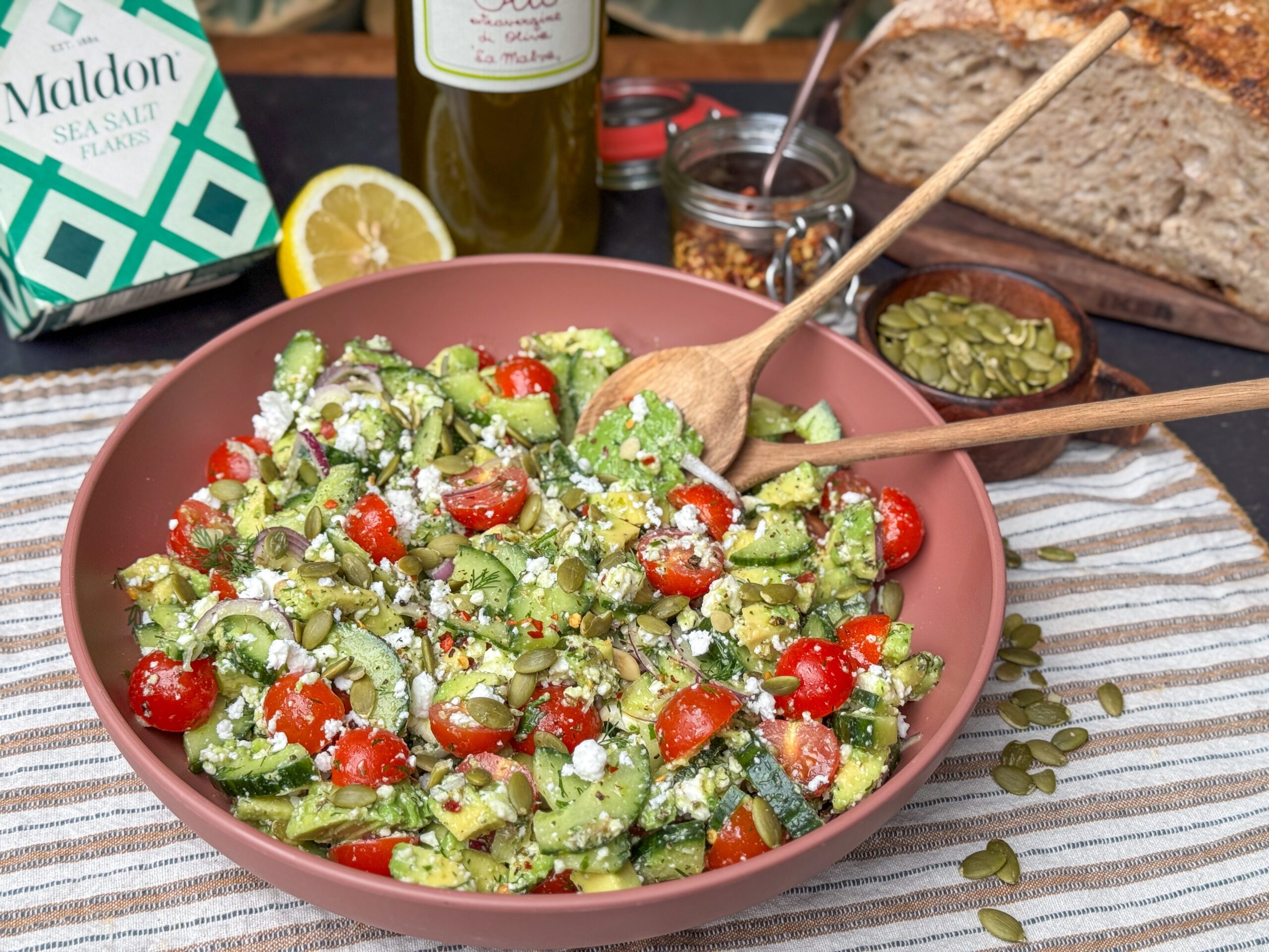 een schaal met een gezonde salade met avocado, feta, tomaatjes en kruidige Italiaanse dressing.