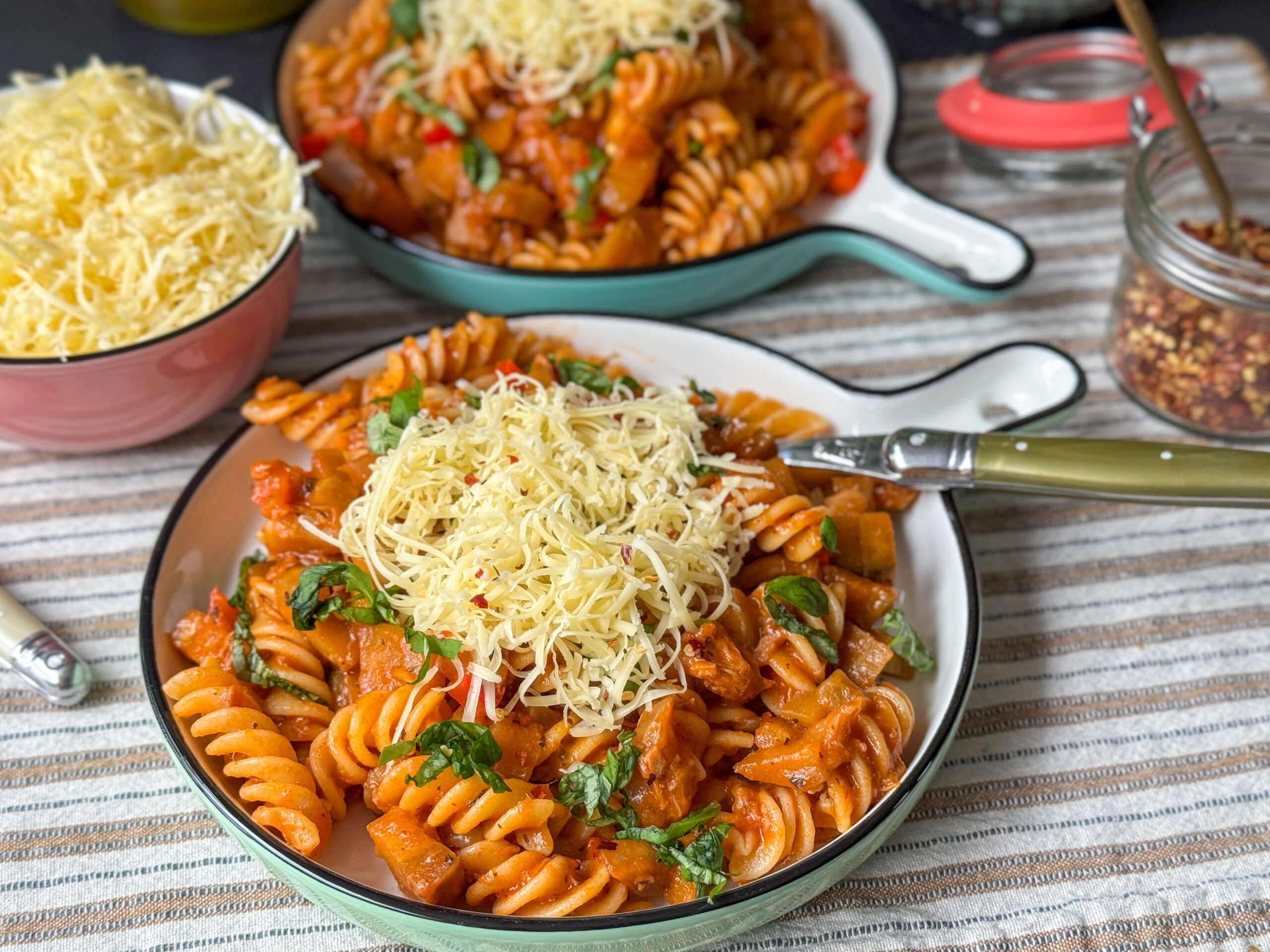 Een heerlijk bord makkelijke pasta met aubergine en tonijn, gegarneerd met verse basilicum en geraspte kaas, klaar om van te genieten."