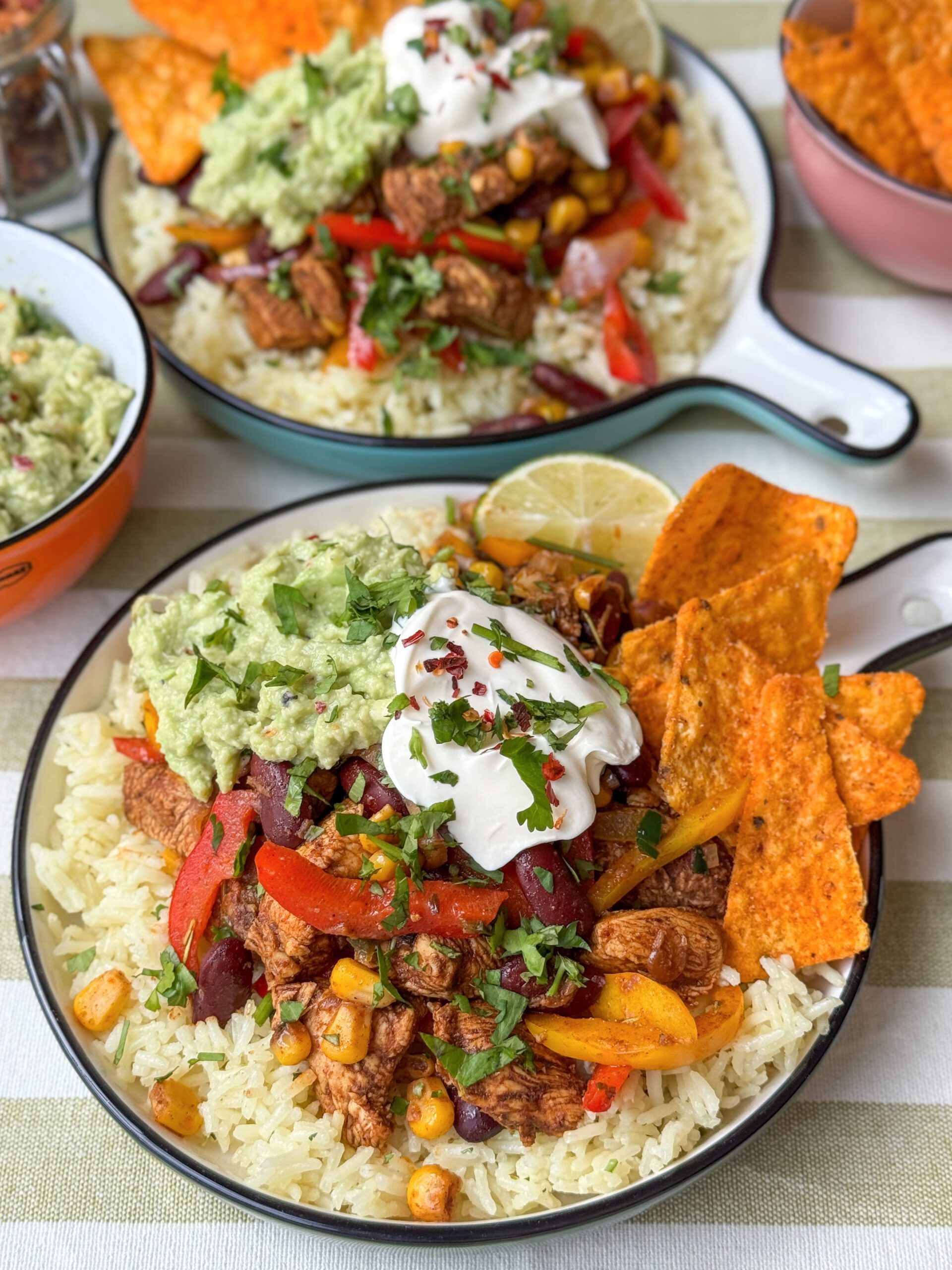Kip fajita met rijst, groenten en toppings zoals guacamole en crème fraîche