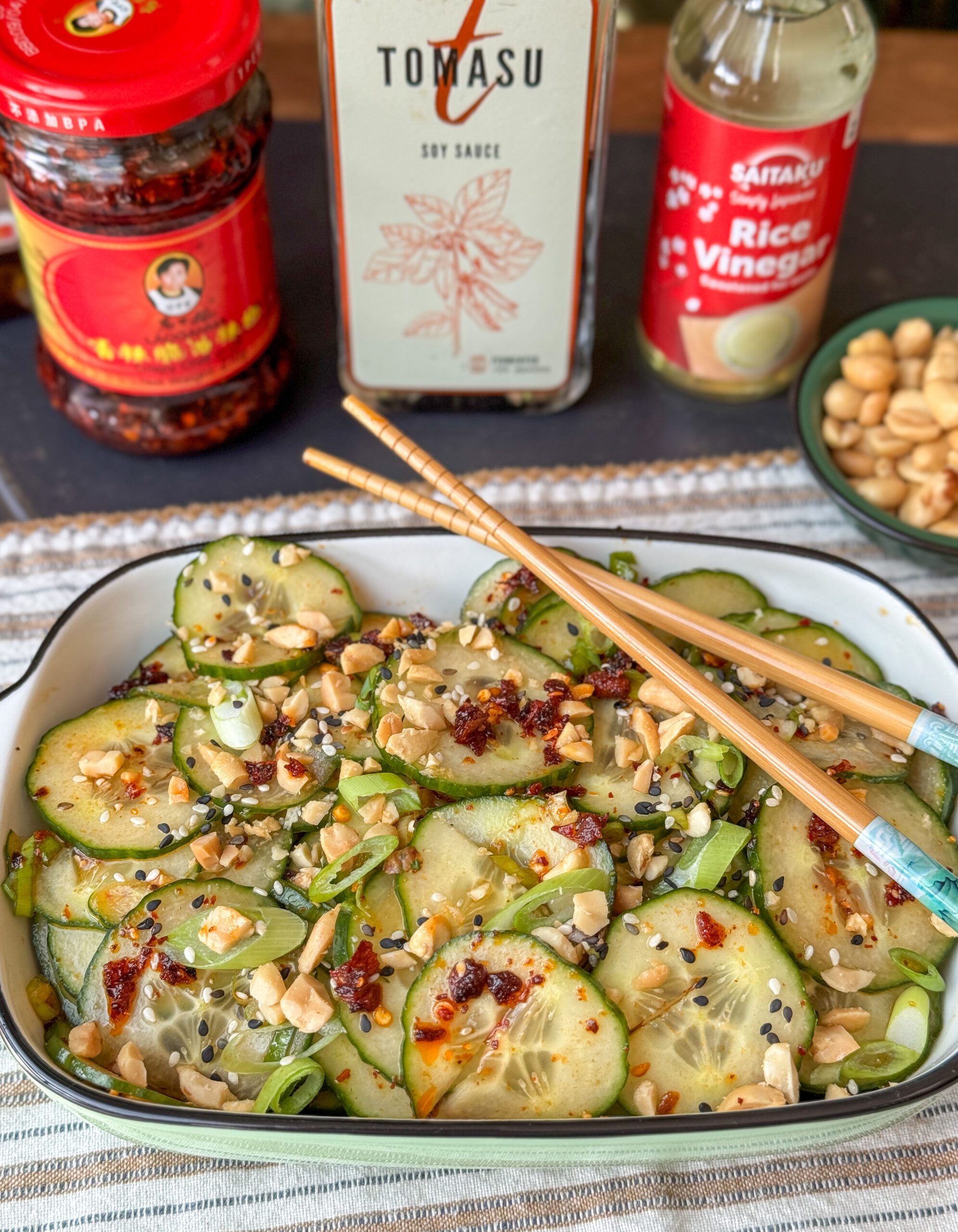 Aziatische komkommersalade met crispy chili olie geserveerd in wit schaaltje met pinda's