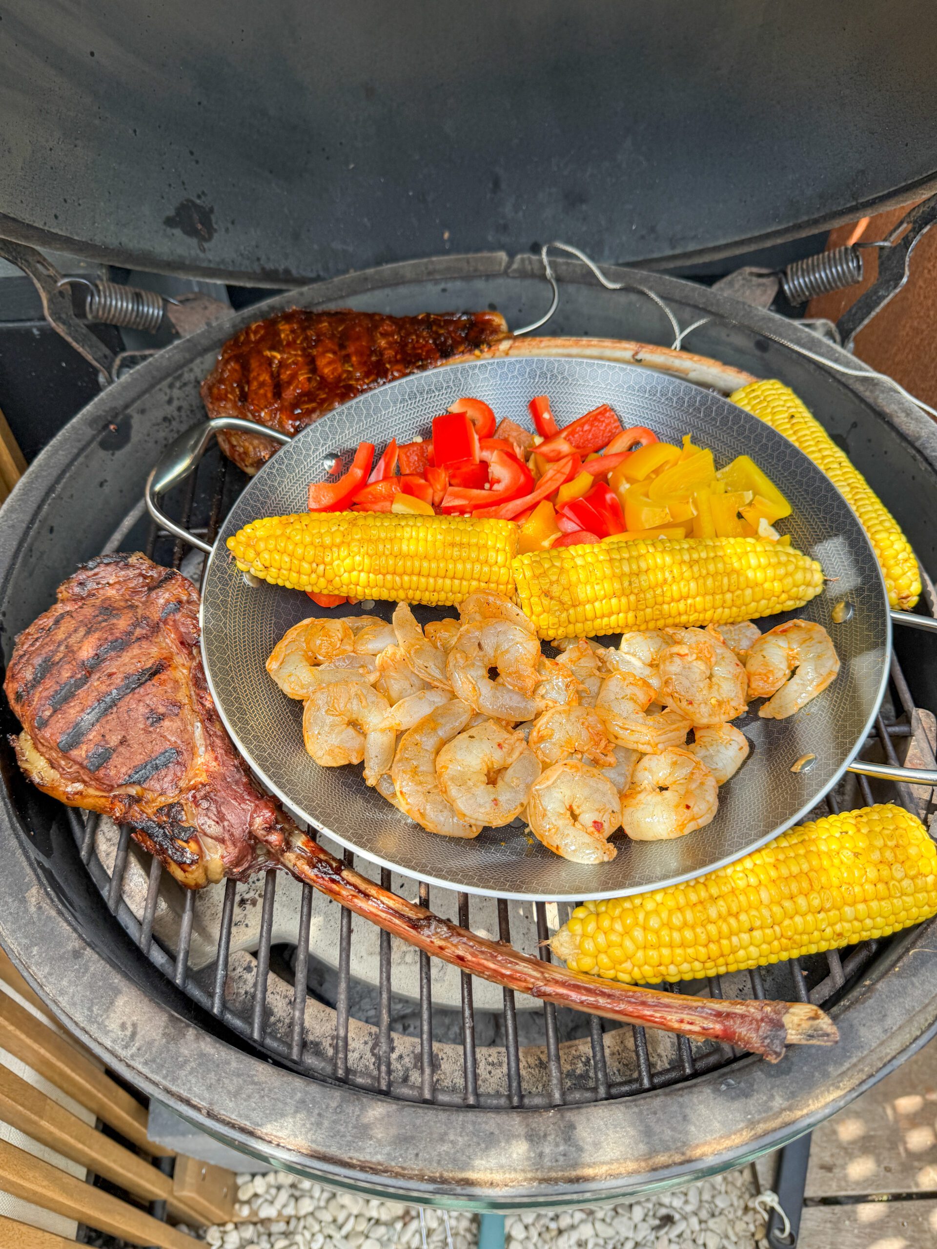 Surf & Turf van de BBQ met tomahawk steak, garnalen en gegrilde mais