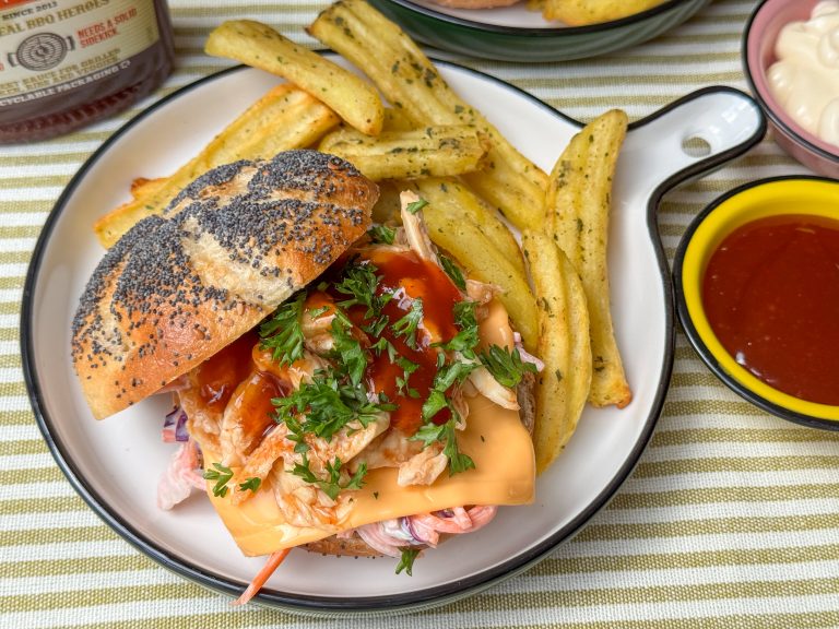 pulled chicken broodje met hot honey bbq saus - geserveerd met coleslaw, cheddar en frietjes op bord