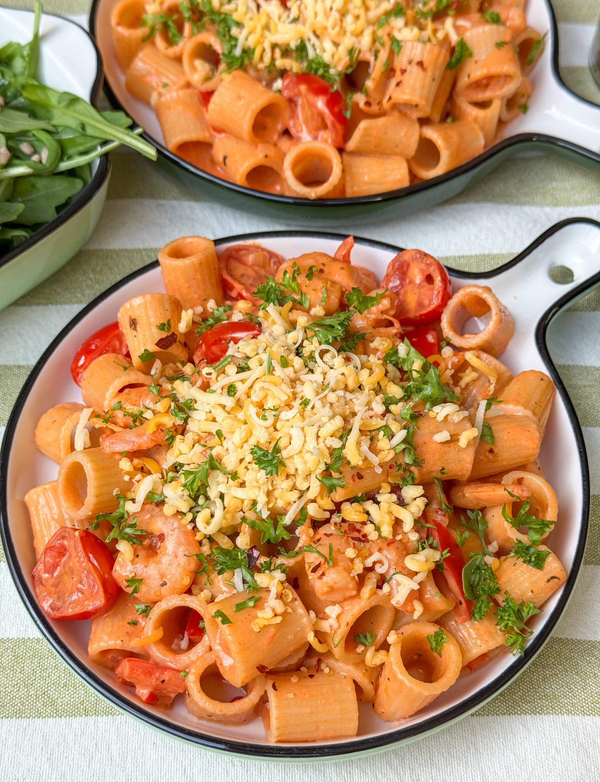 pasta met garnalen recept - romige tomatensaus met cajunkruiden, geserveerd met kaas en peterselie op rond bord