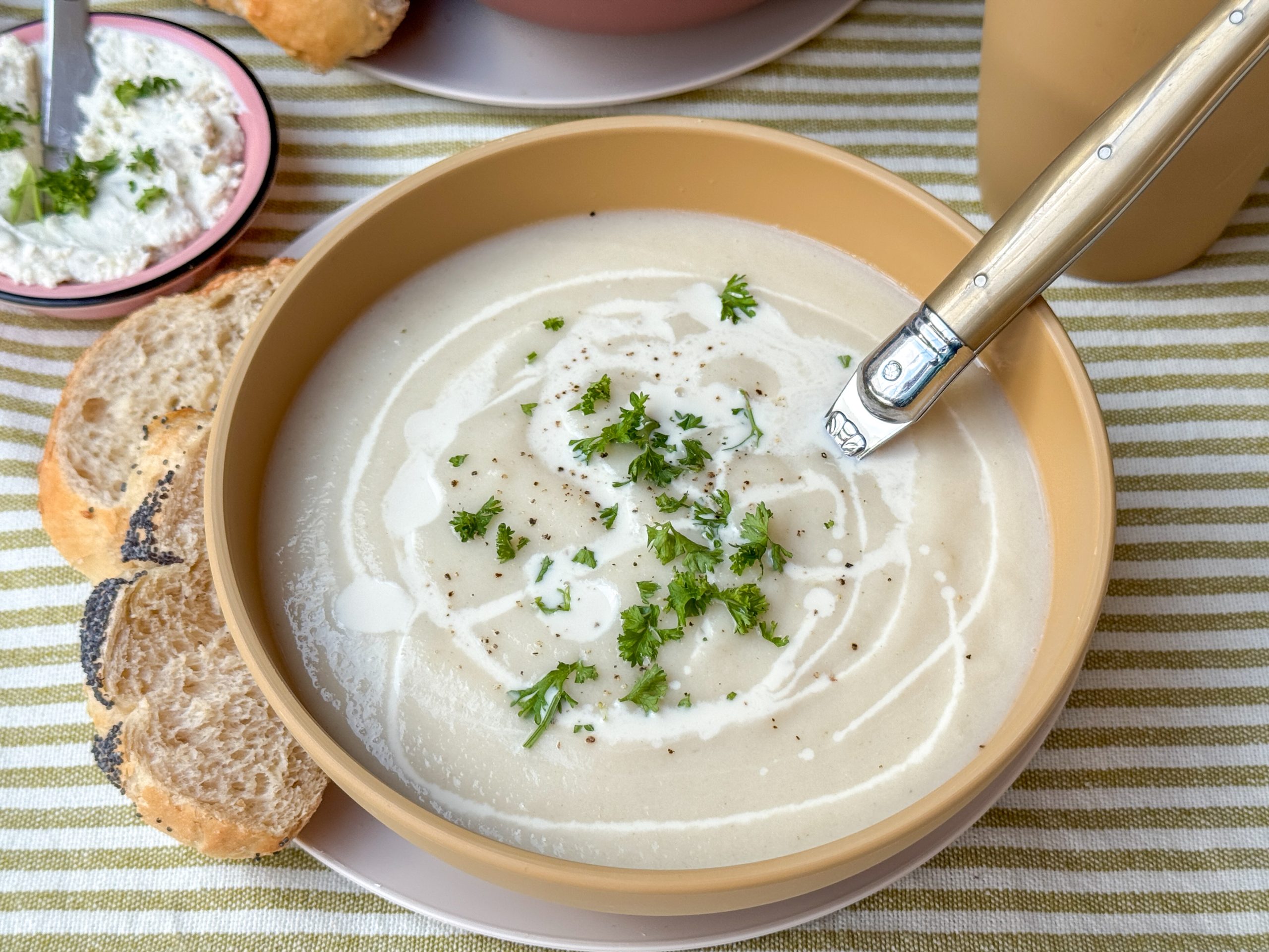 bloemkoolsoep recept - romige soep geserveerd in lichtgele kom met verse peterselie