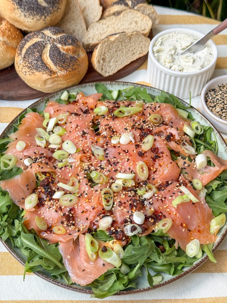 Zalm carpaccio close-up met pittige Aziatische dressing en crispy chili olie, geserveerd met rucola