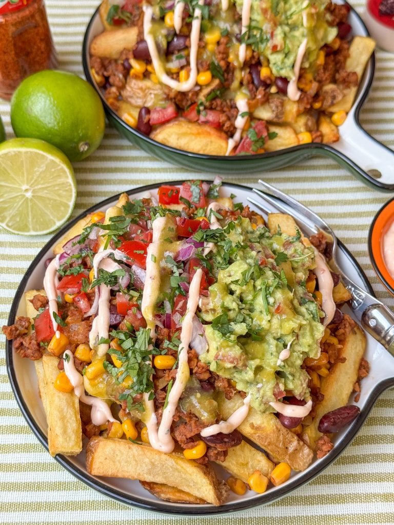 Mexicaanse loaded fries recept met sriracha mayonaise, feta, pico de gallo en en guacamole op een wit bord