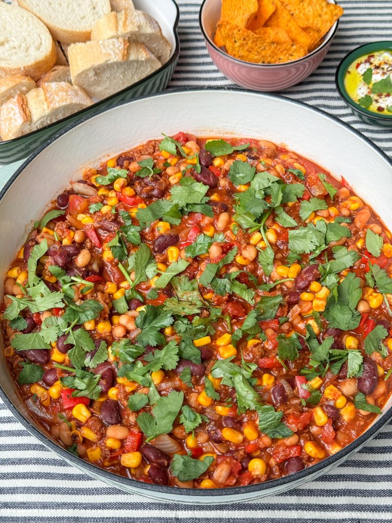 vegetarische chili con carne geserveerd met stokbrood, tortillachips en yoghurtdip