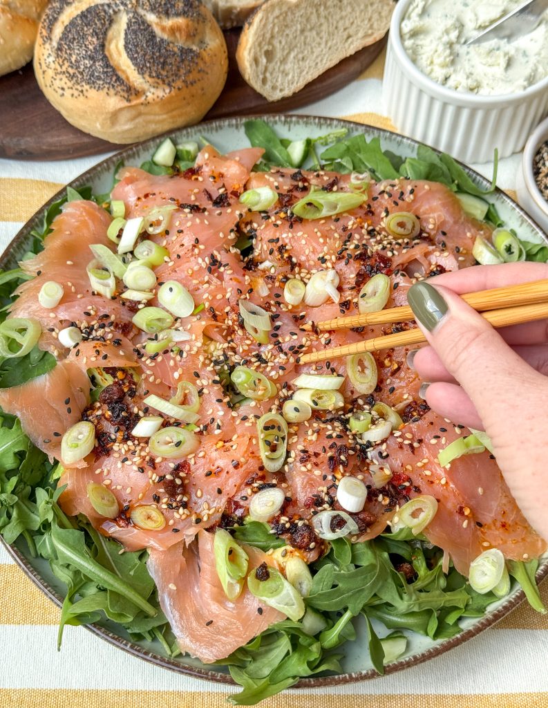 zalm carpaccio recept met aziatische dressing en crispy chili olie, geserveerd op bord met stokjes 