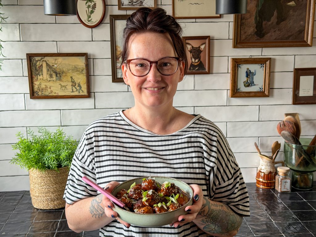 Marie Louise houdt een kommetje met Koreaanse gehaktballetjes in sticky gochujang saus vast in de keuken