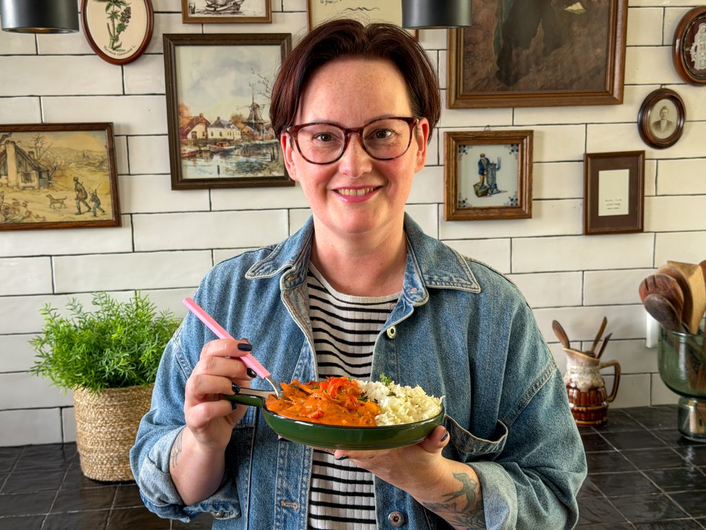 Marie Louise houd en bord romige kipstoof met rijst vast in de keuken