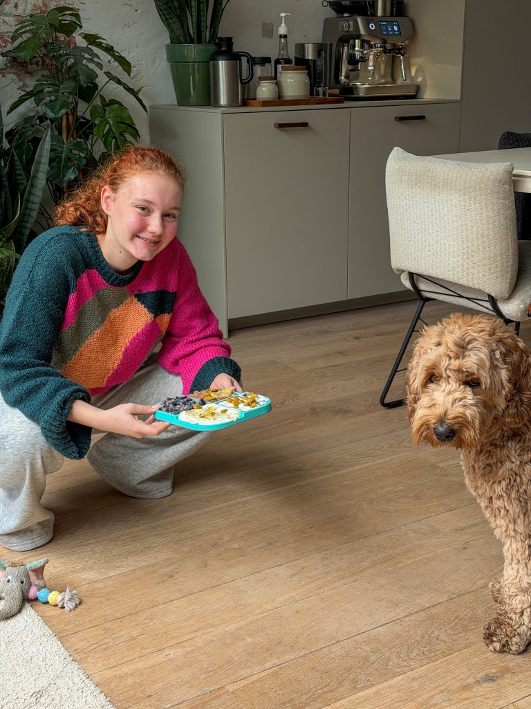 Amaranthe houdt een snackbordje vast terwijl Teun nieuwsgierig toekijkt.