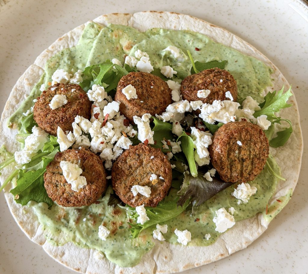wrap belegd met falafel, avocado-dip en feta op rond bord