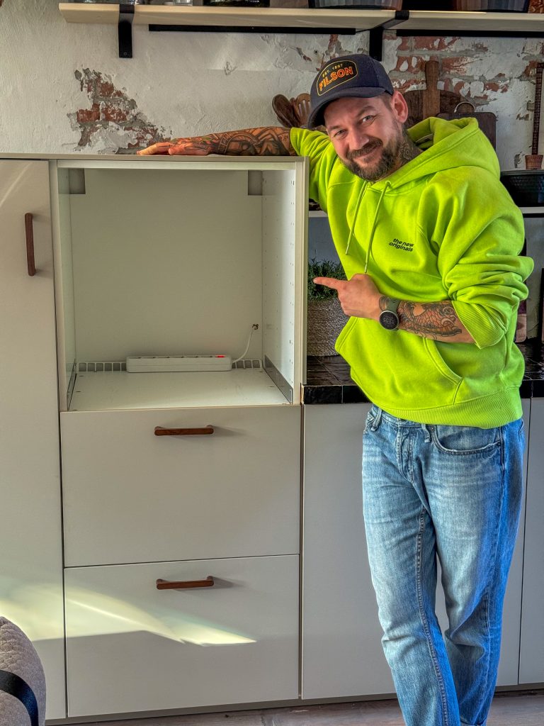 Jan Willem wijst trots naar het nieuwe lege kastvak in de keuken.