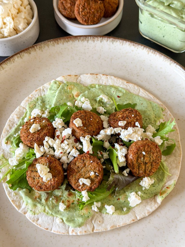 Verkruimelde feta toegevoegd aan de wrap met falafel en sla