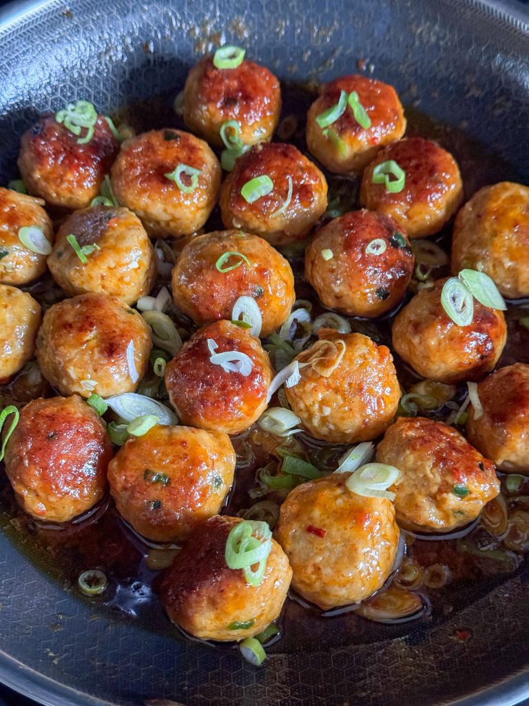 Balletjes in de pan zijn omhuld met sweet chilisaus en bosui