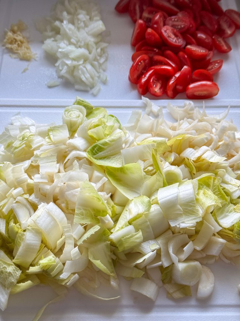 Witlof, ui, knoflook en tomaat gesneden voor pasta