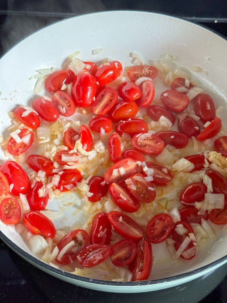 Ui, knoflook en tomaat bakken in de pan