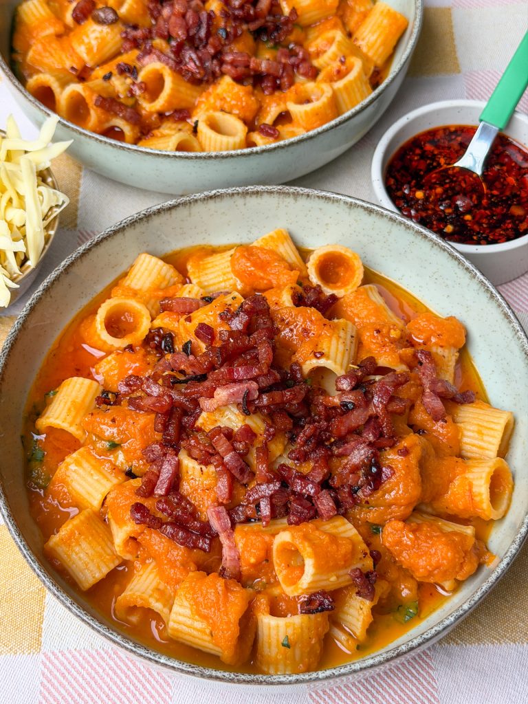 Pasta in pompoensaus geserveerd in kom met spekjes en crispy chili olie