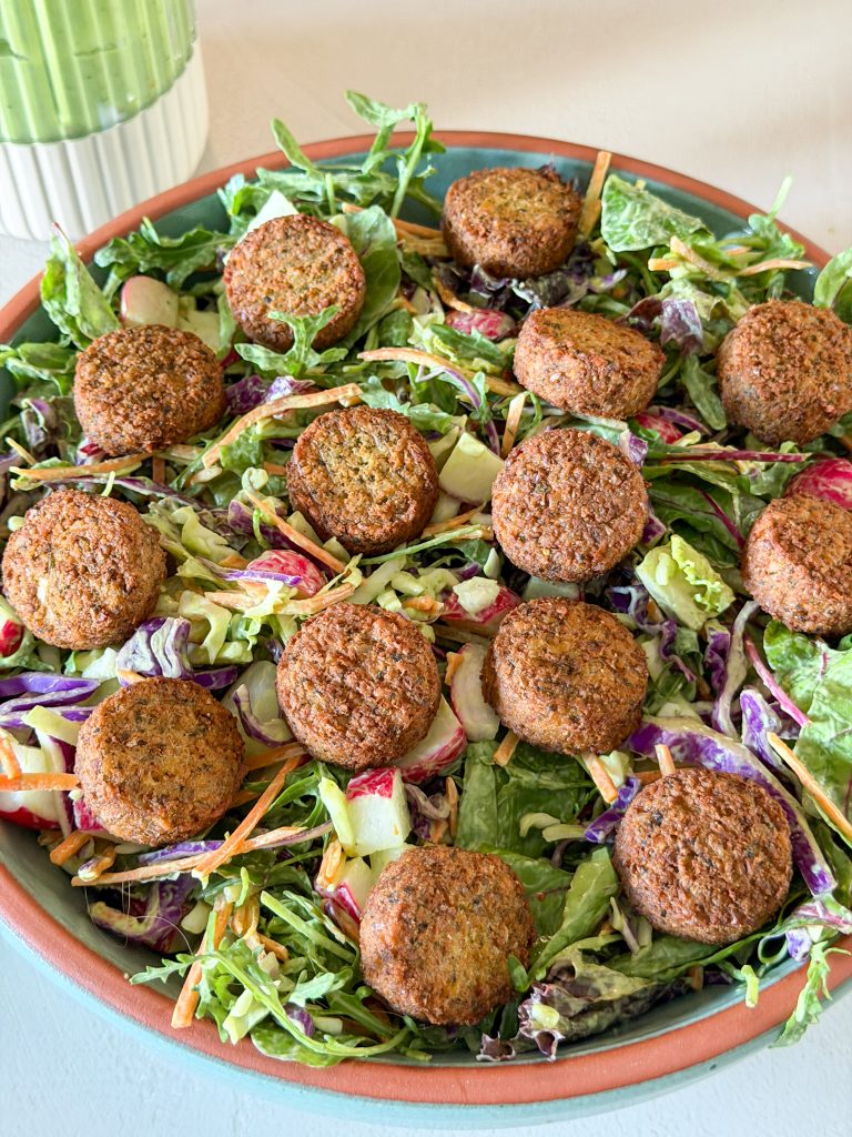 Falafel verdeel over salade met sla, koolmix en radijs