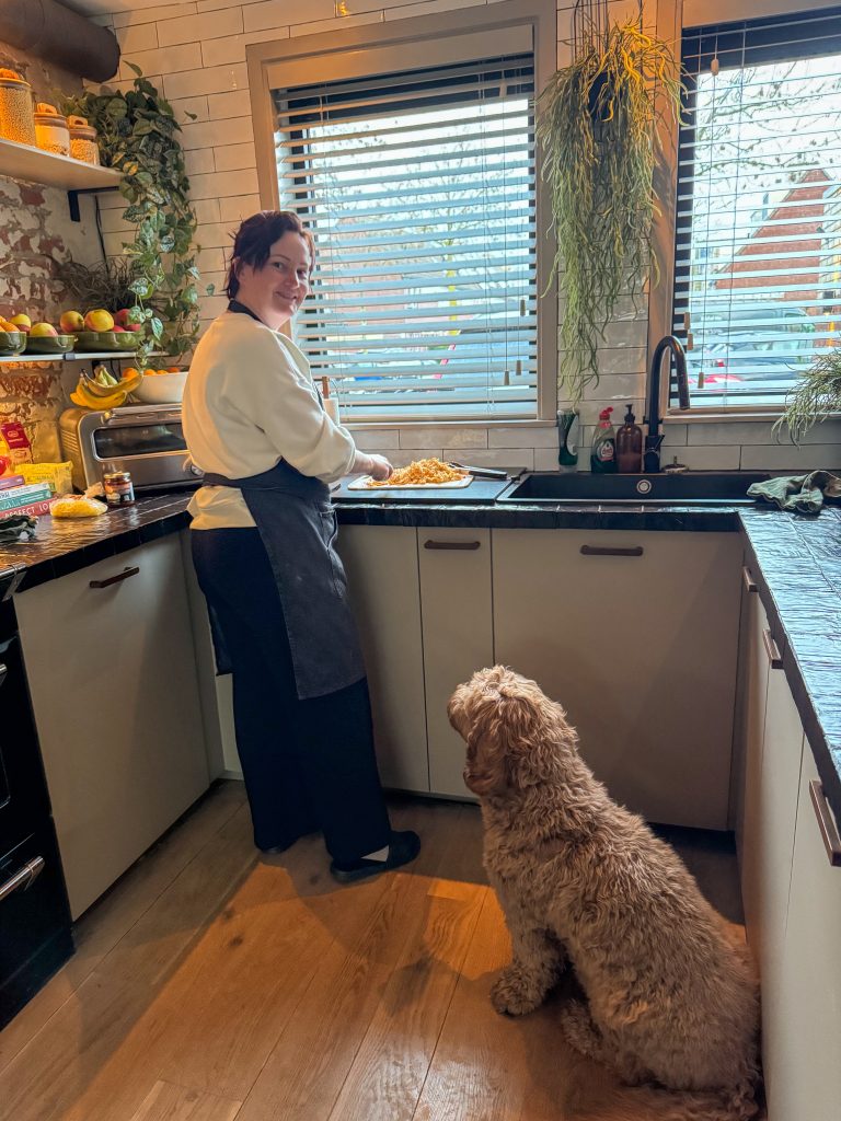 Marie Louise staat te koken in de keuken terwijl de hond toekijkt