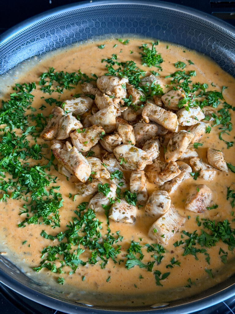 Kruidige roomsaus met kip en peterselie in pan