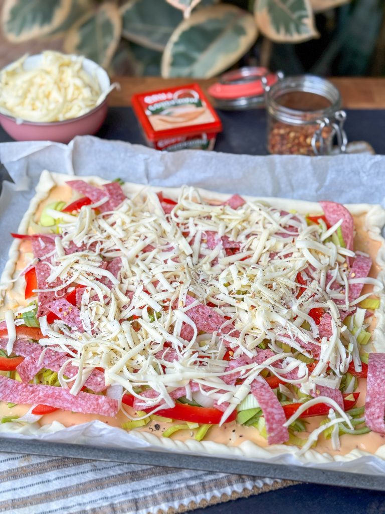 Plaattaart salami bestrooien met kaas