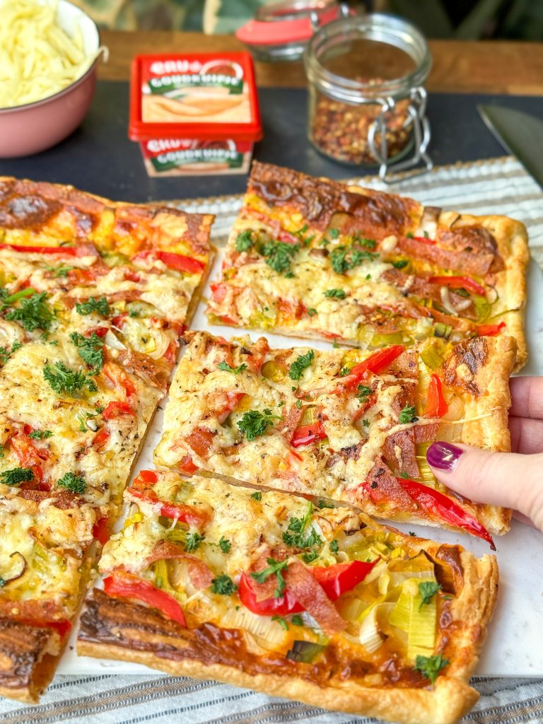 Stuk plaattaart met pittige smeerkaas, groenten en salami dat wordt opgepakt