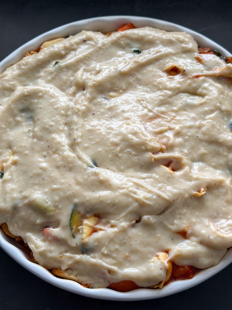 Bechamelsaus verdelen over de ravioli ovenschotel