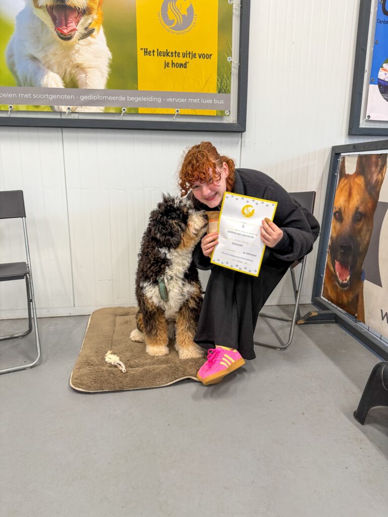 Amaranthe knuffelt Ledgie en houdt zijn diploma van de hondentraining vast.
