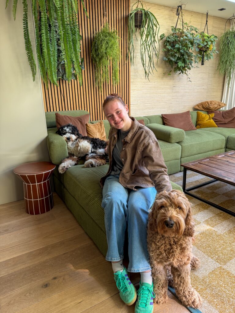 Amaranthe zit op de groene bank in onze woonkamer met Teun aan haar voeten en Ledgie naast haar.