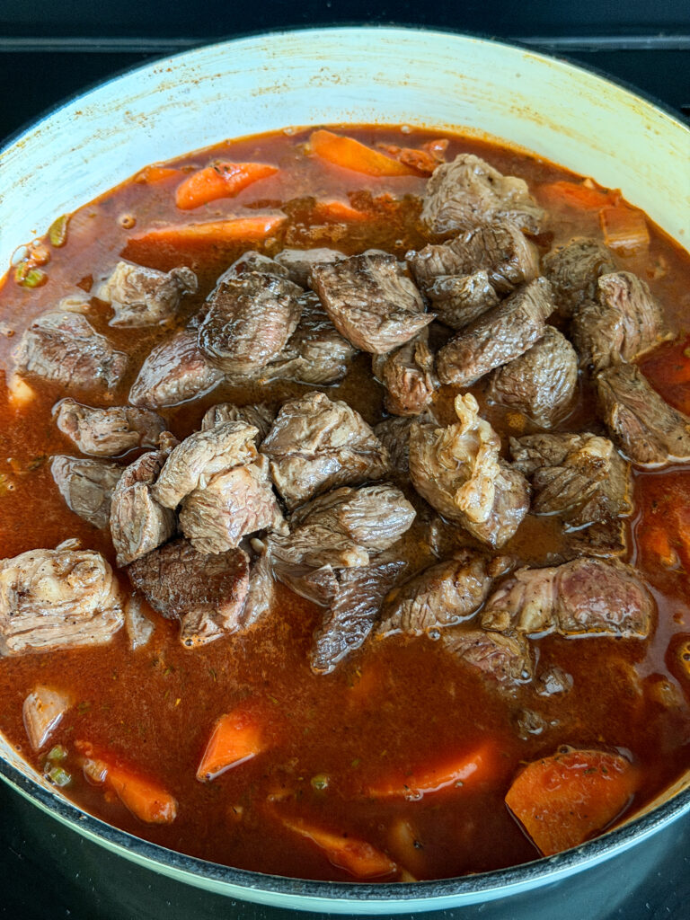 Vlees en spek terug in de pan, klaar om te stoven