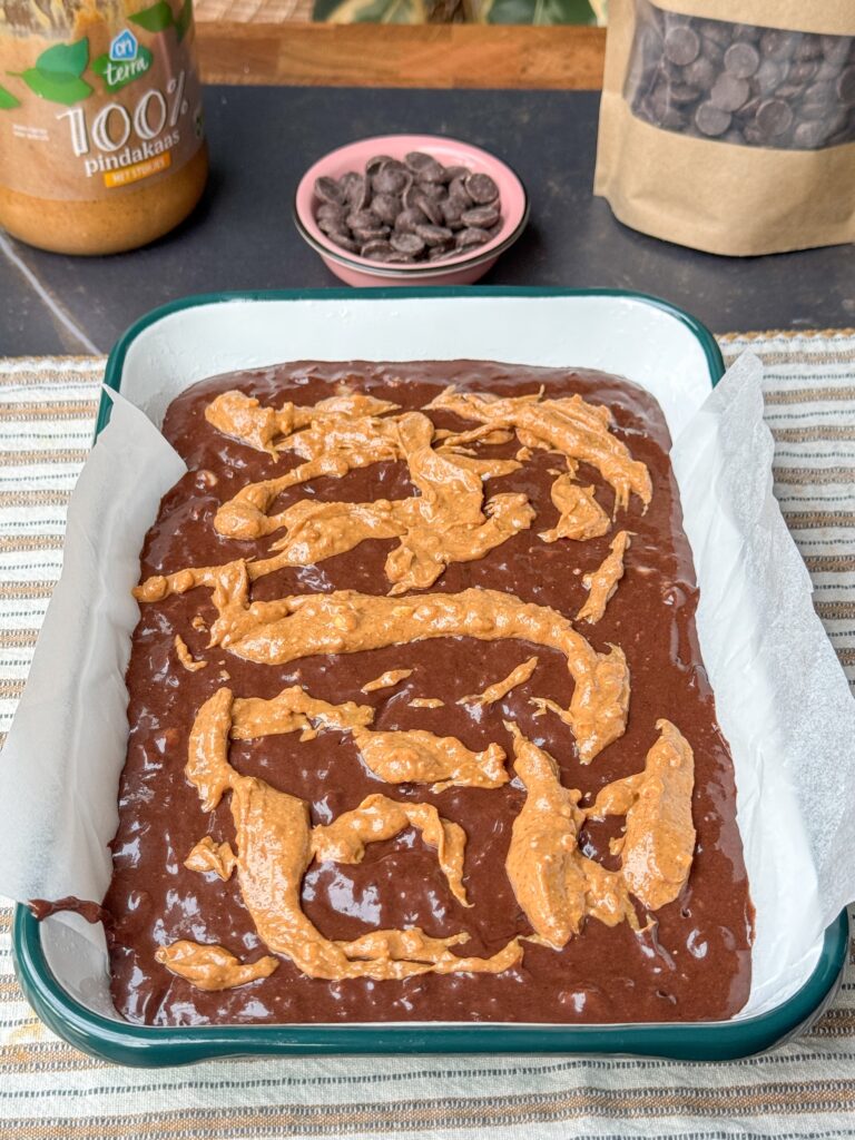 Pindakaas verdeeld over brownie beslag met banaan