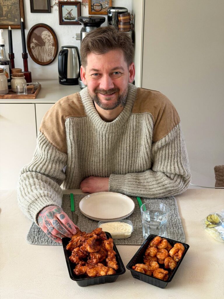 Jan Willem zit aan tafel met kibbeling en kijkt in de camera.