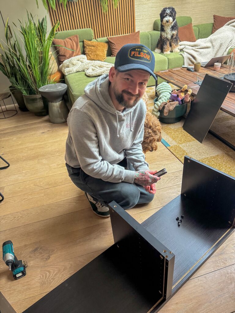 Jan Willem monteert een meubel in de woonkamer.