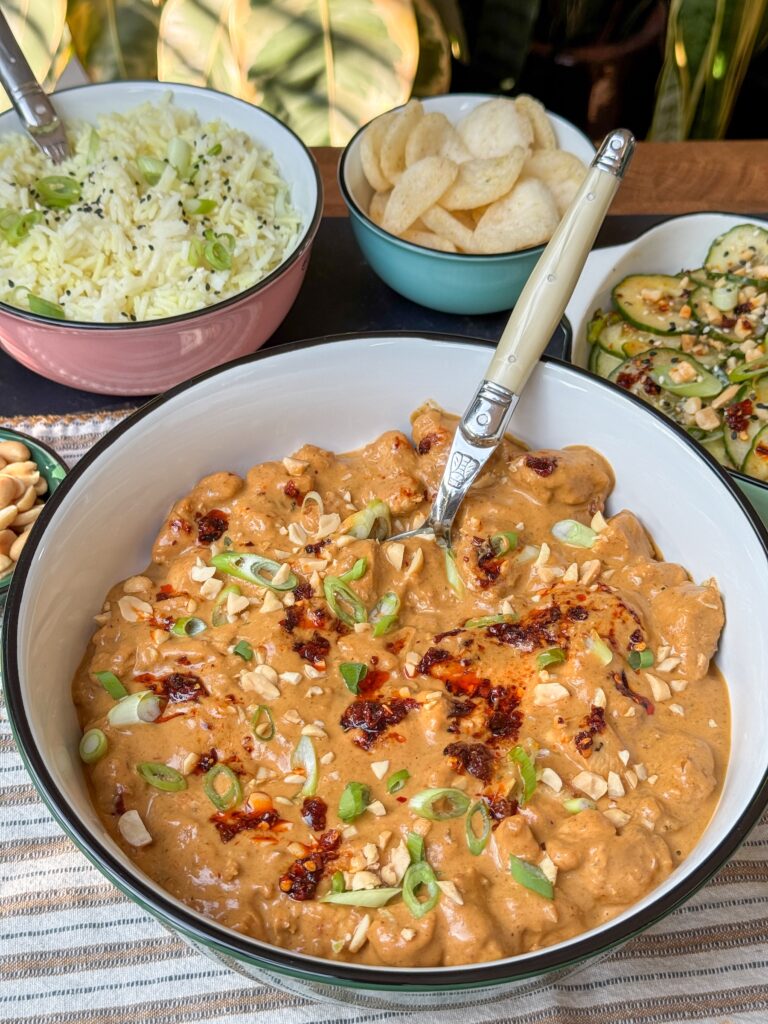 Schaal met romige pindasaus, gebakken kipdijfilet en bosui