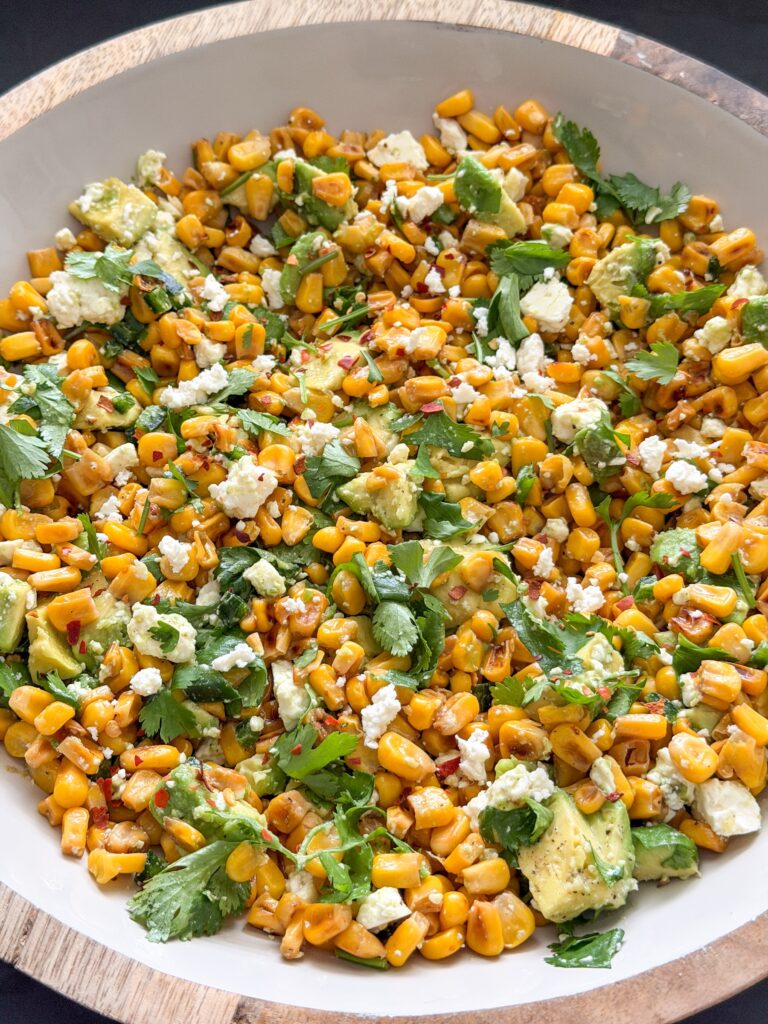 Alle ingrediënten gemengd voor de maissalade met Mexicaanse twist in een schaal