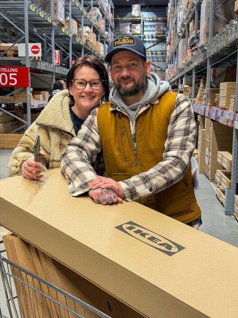 Marie Louise en Jan Willem bij IKEA met een grote doos in de winkelwagen.