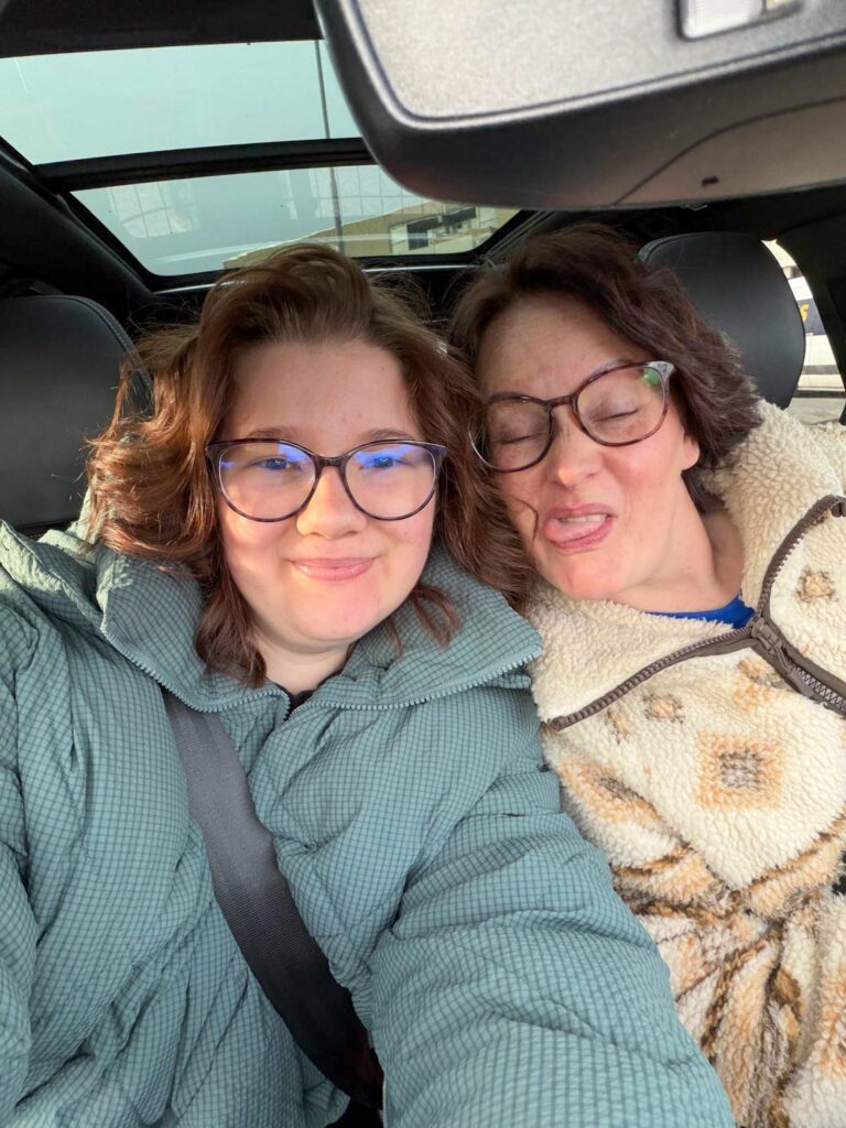 Marie Louise en Beaudine poseren speels in de auto.