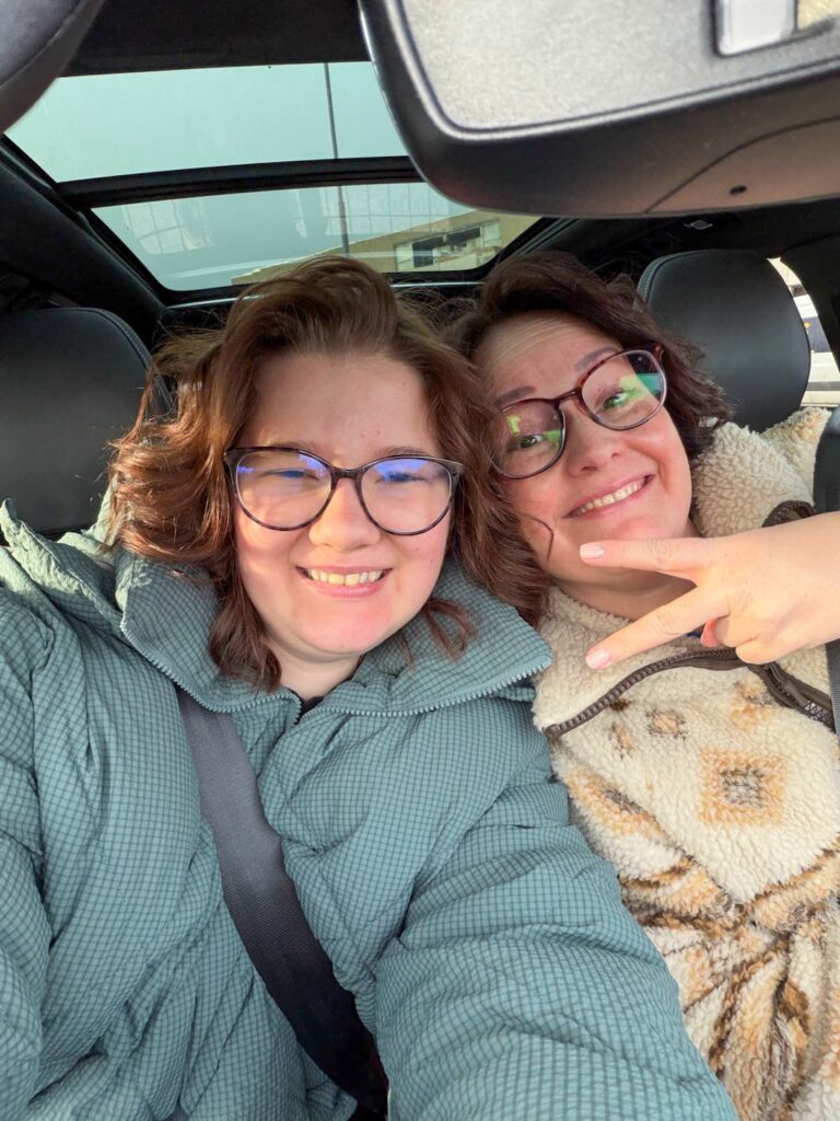 Beaudine en Marie Louise samen in de auto, lachend voor een selfie.