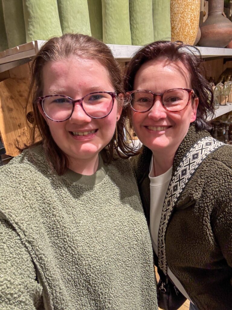 Moeder en dochter maken samen een glimlachende selfie in een woonwinkel tussen interieur accessoires