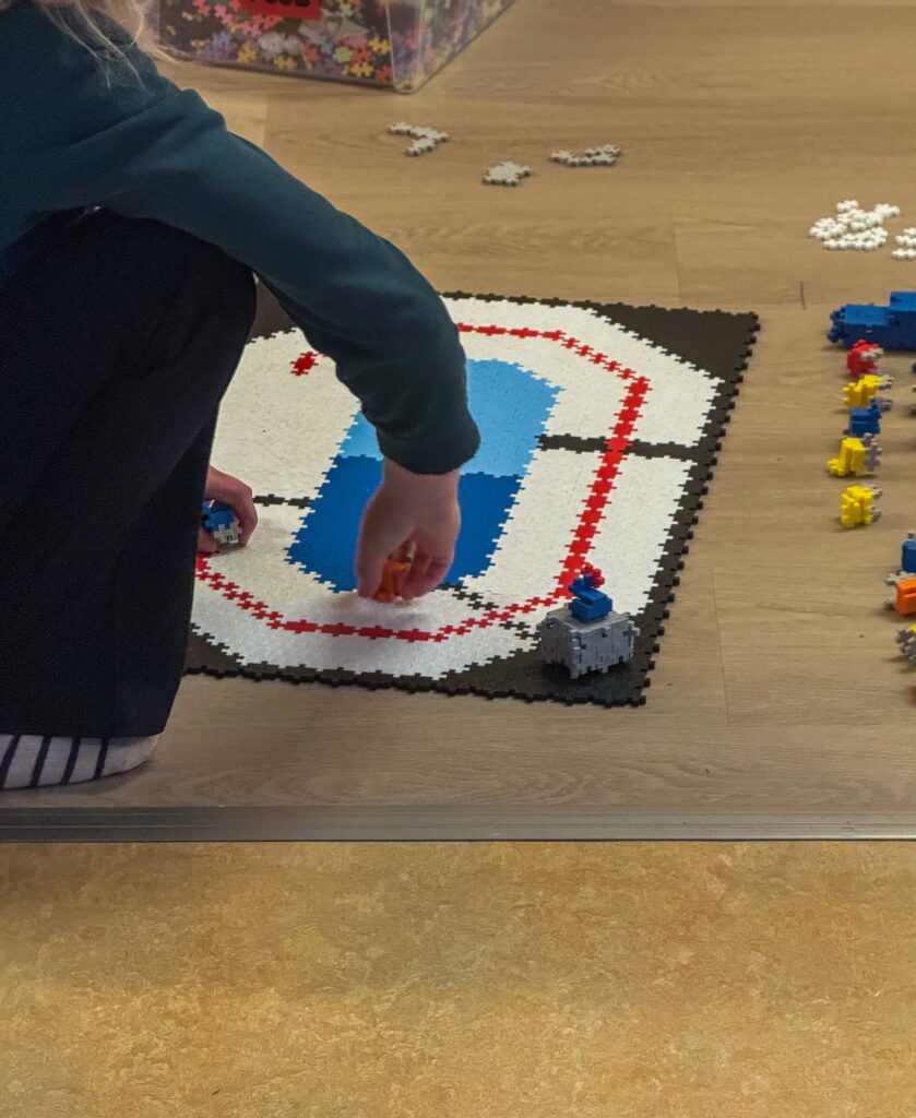 Kind speelt met bouwblokken op een speelmat op de vloer.