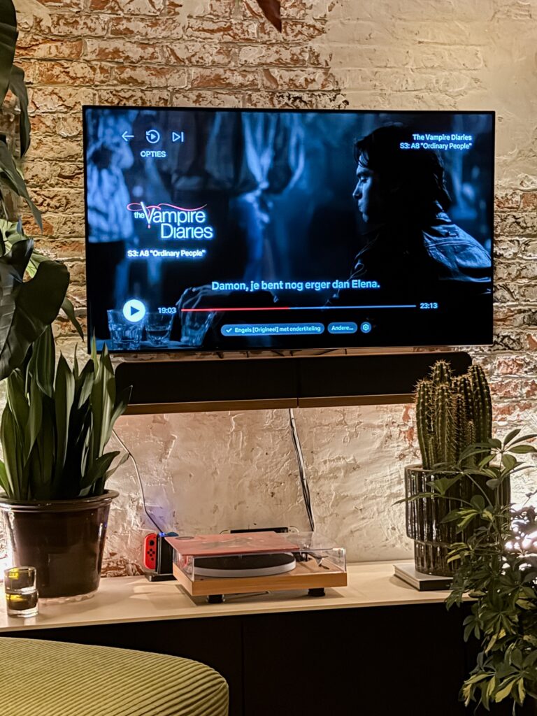 Televisie met The Vampire Diaries op het scherm in een woonkamer met veel planten