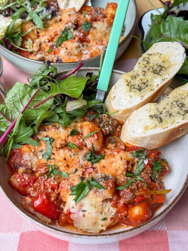 Pittige vegetarische gnocchi ovenschotel serveren met salade en kruidenstokbrood