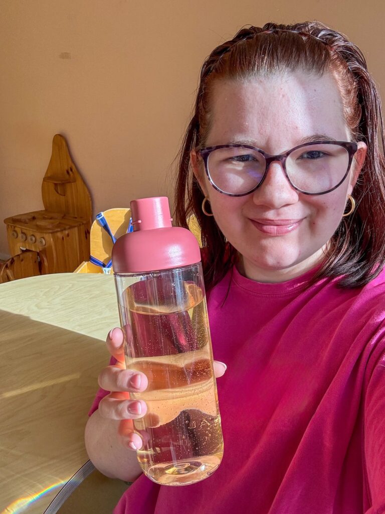 Beaudine drinkt water uit een fles in de zon