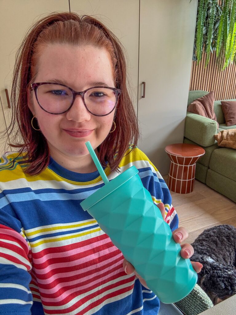 Beaudine met een turquoise drinkbeker in de woonkamer